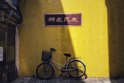 黑色城市自行车停在黄色的墙
